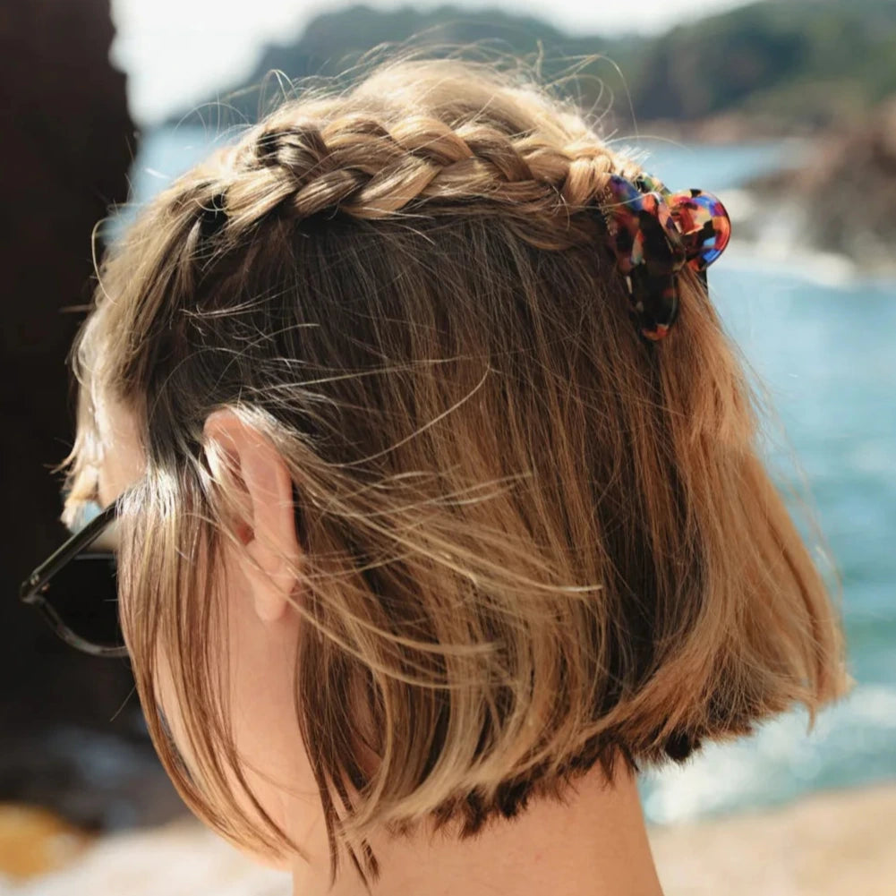 Petite pince à cheveux en forme de nuage à motifs écaille multicolore portée avec des tresses sur cheveux courts.