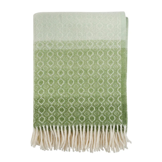 Plaid en laine d'agneau avec des motifs blancs sur un fond dégradé vert.