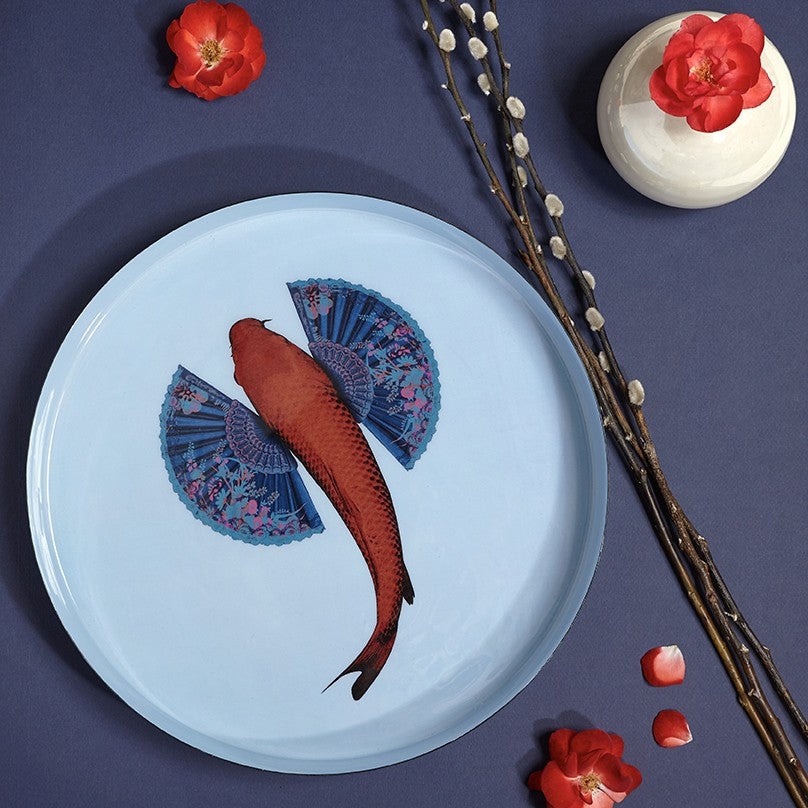 Plateau rond en métal, modèle Fishkoi, fond bleu clair. 
