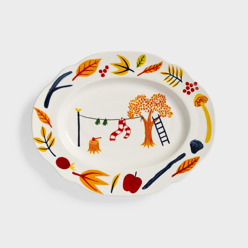 Plat ovale automnal dans les tons oranges et jaunes avec des dessins de feuilles mortes. 