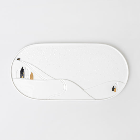 Plat de service en porcelaine émaillée avec un dessin légèrement en relief d'un paysage enneigé.