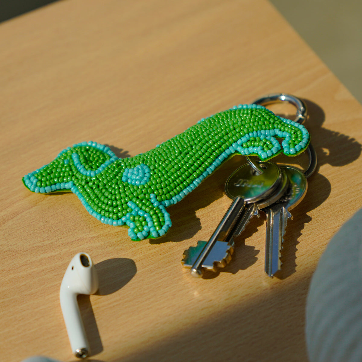 Porte-clé en broderie perlée rembourrée, en forme de chien vert et bleu.