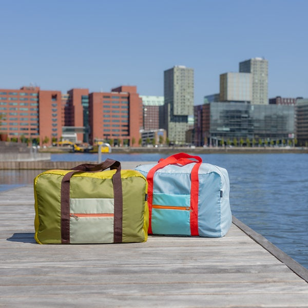 Duo de sacs de loisirs posés sur un ponton, coloris vert et bleu.