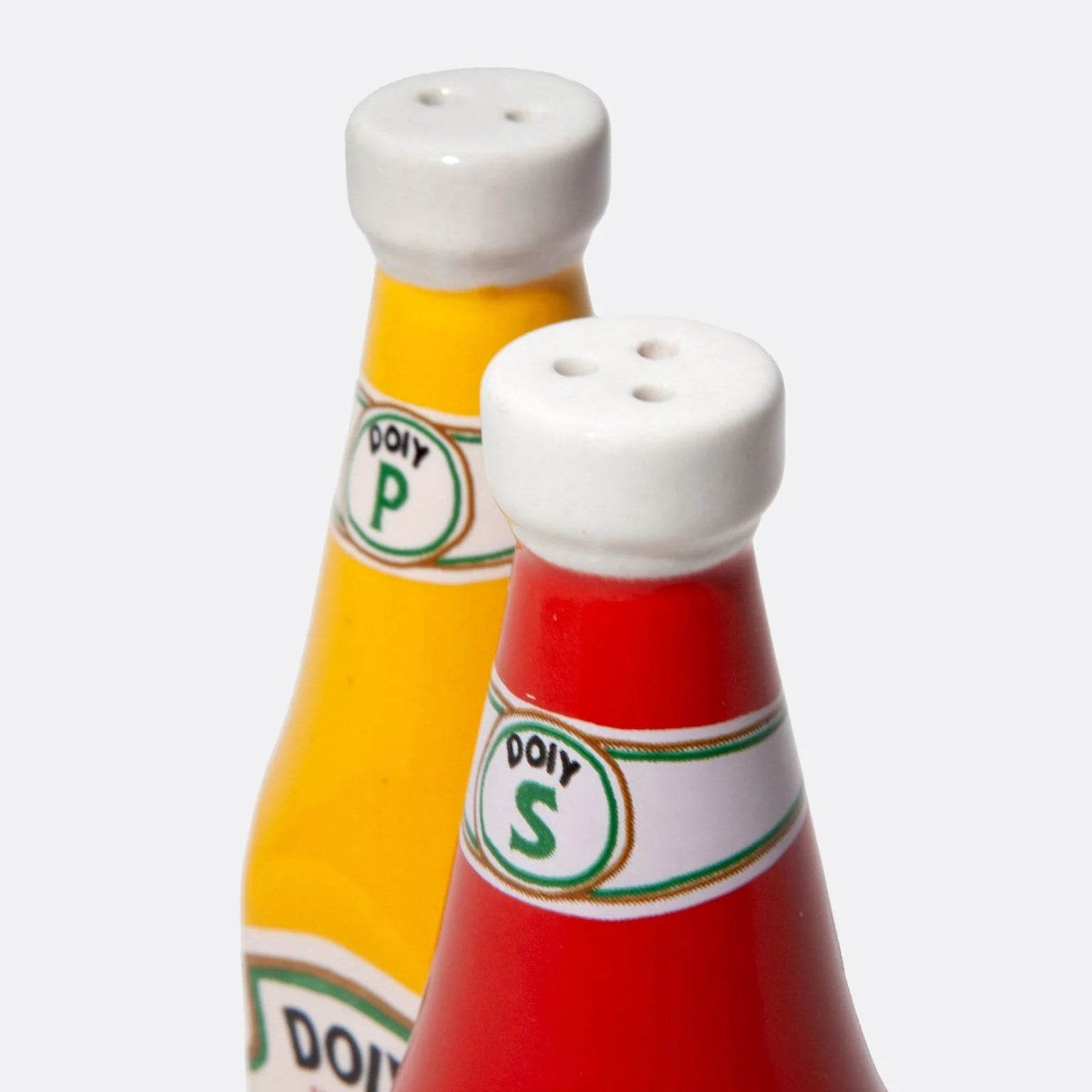Zoom sur le set de salière et poivrier en forme de bouteilles de ketchup et de moutarde, rouge et jaune en céramique.
