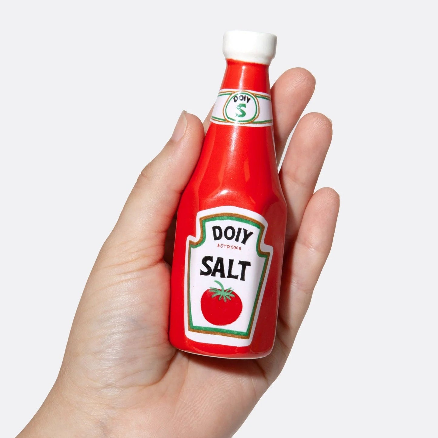 Salière ou poivrier en forme de bouteille de ketchup rouge en céramique tenue dans une main. 