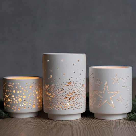 Set de 3 photophores blancs en porcelaine ajourés de motifs hivernaux.