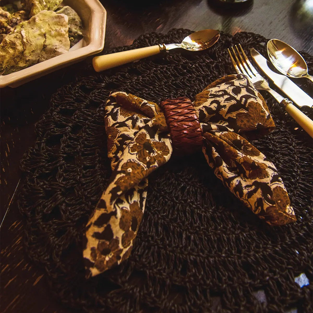 Set de table rond en raphia noir avec des détails au crochet, posé sur une table.
