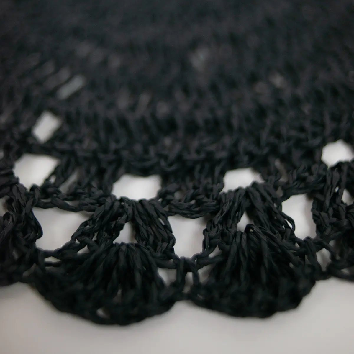Set de table rond en raphia noir avec des détails au crochet.