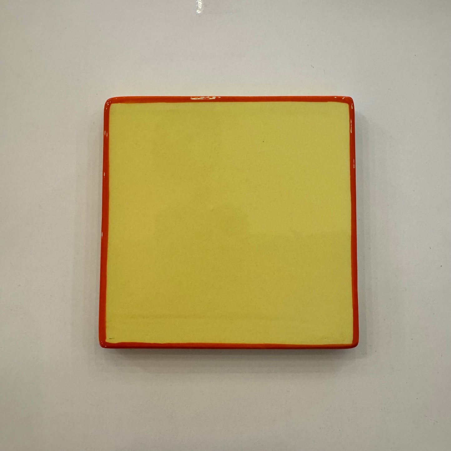 Sous-verre en céramique carré jaune et orange.