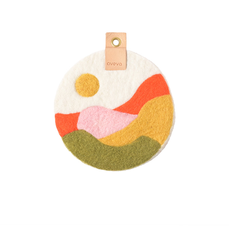 Tableau rond en laine avec un paysage de champs suédois, coloris orange, jaune, blanc, rose et vert kaki.