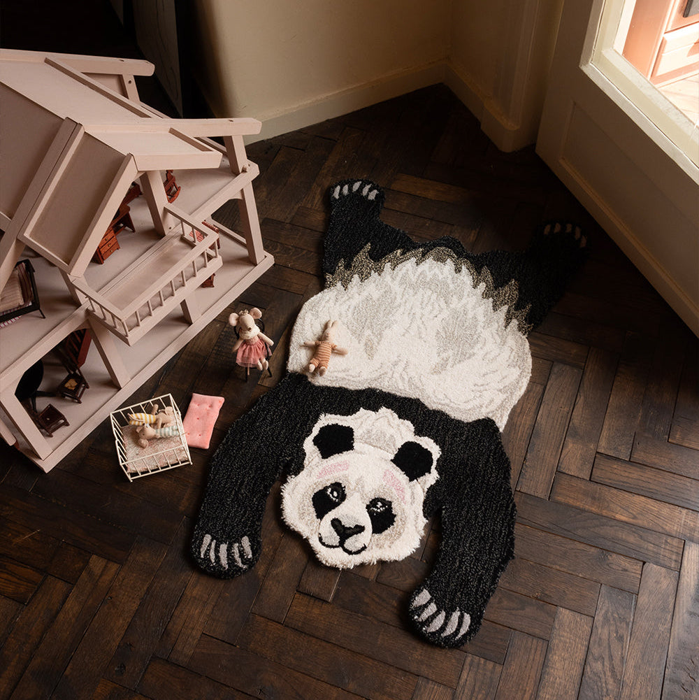 Tapis en forme de panda posé dans une chambre d'enfant au pied d'une maison de poupée.