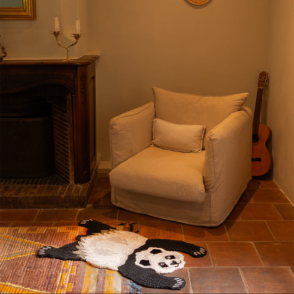 Tapis en forme de panda posé au pied d'un fauteuil.