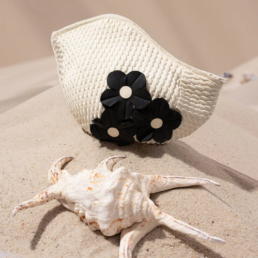 Trousse de toilette en forme de bonnet de bain blanc avec des fleurs noires.