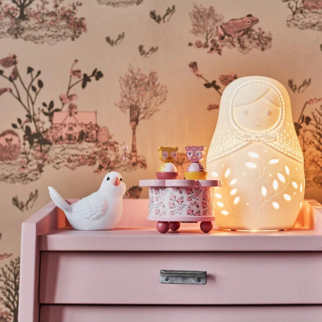 Veilleuse en porcelaine en forme de poupée russe posée sur une étagère dans une chambre d'enfant.