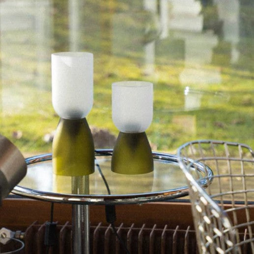 Deux lampes en verre recyclé vert clair de la marque Q de bouteilles posées sur une table 