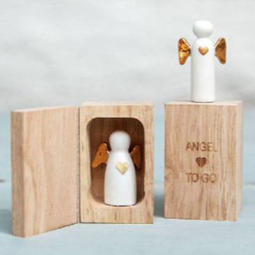Minis anges en porcelaine blanche avec les ailes dorés posés dans ou sur leur boîte.